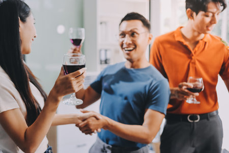 Asian office colleagues and friends enjoy a daytime BBQ with pizza and beer, creating a lively atmosphere filled with joy.の写真素材