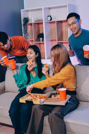 Happy young friends group having lunch at home. Asia family party eating pizza food and laughing enjoying meal while sitting at dining table together at house. Celebration holiday and togetherness.の写真素材