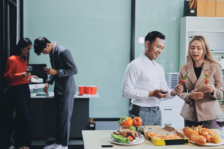 Asian office colleagues and friends enjoy a daytime BBQ with pizza and beer, creating a lively atmosphere filled with joy.の写真素材