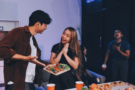 Happy young friends group having lunch at home. Asia family party eating pizza food and laughing enjoying meal while sitting at dining table together at house. Celebration holiday and togetherness.の写真素材