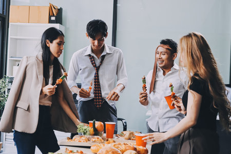 Asian office colleagues and friends enjoy a daytime BBQ with pizza and beer, creating a lively atmosphere filled with joy.の写真素材