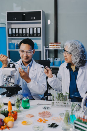 Team Asian scientists in a lab conducting food research using a microscope and lab equipment,...