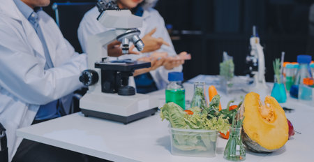 Team Asian scientists in a lab conducting food research using a microscope and lab equipment,...