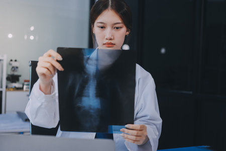 Medical health clinic beautiful Asian doctor working using smart tablet touching, stethoscope diagnosing patient analysis research examination healthcare provider service insurance in modern officeの写真素材