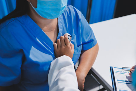 Homecare nursing service and elderly people cardiology healthcare. Close up of young hispanic female doctor nurse check mature caucasian man patient heartbeat using stethoscope during visitの写真素材