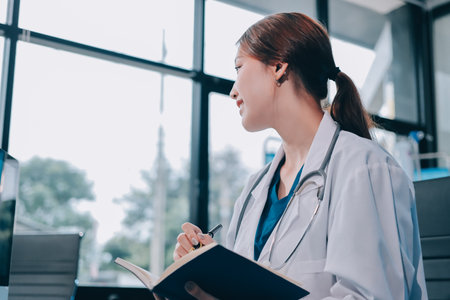 Medical health clinic Asian doctor working using smart tablet touching, stethoscope diagnosing patient analysis research examination healthcare provider service insurance in modern officeの写真素材