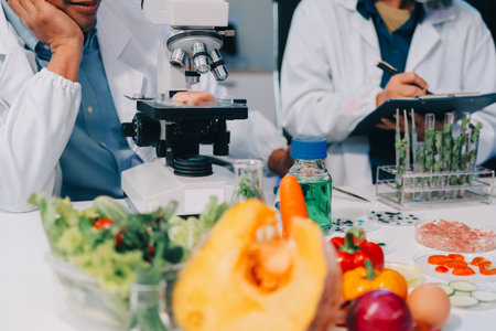 Team Asian scientists in a lab conducting food research using a microscope and lab equipment,...