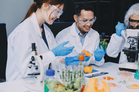 Team Asian scientists in a lab conducting food research using a microscope and lab equipment, showcasing innovation in food science and biotechnologyの写真素材