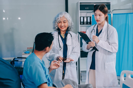 Nurse giving assistance to senior patient with disease in bed. Medical assistant and doctor doing healthcare checkup for pensioner with oxygen tube and IV drip bag in hospital ward.の写真素材