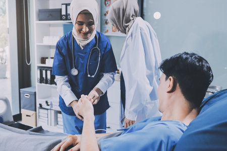A young man lies on a bed in a hospital ward talking with his doctor. Doctor checking patient's health doctor treating patient, hospital admission of patientの写真素材