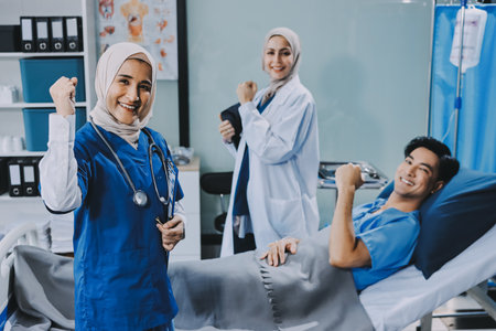 A young man lies on a bed in a hospital ward talking with a young doctor. Doctor checking patient's health doctor treating patient, hospital admission of patientの写真素材