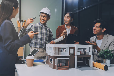 Construction, planning and architects meeting about design of building, strategy and working in industrial collaboration. Architecture workers talking about maintenance project with paper and a modelの写真素材