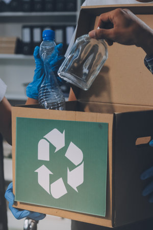 Close-up of female hands from a family collecting plastic waste and bottles from the ground. They wear gloves and focus on recycling to help reduce plastic pollution and protect the environment.の写真素材