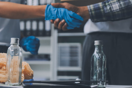 Close-up of hands from a family collecting plastic waste and bottles from the ground. They wear gloves and focus on recycling to help reduce plastic pollution and protect the environment.の写真素材