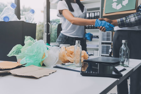 Close-up of female hands from a family collecting plastic waste and bottles from the ground. They wear gloves and focus on recycling to help reduce plastic pollution and protect the environment.の写真素材
