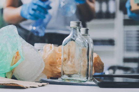 Close-up of female hands from a family collecting plastic waste and bottles from the ground. They wear gloves and focus on recycling to help reduce plastic pollution and protect the environment.の写真素材