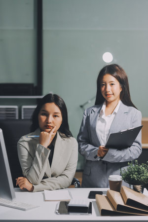 Asian Businesswoman Using laptop computer and working at office with calculator document on desk, doing planning analyzing the financial report, business plan investment, finance analysis concept.の写真素材