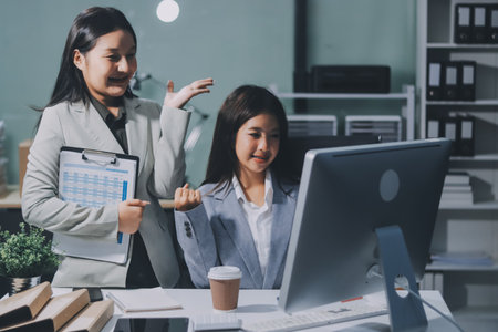 Asian Businesswoman Using laptop computer and working at office with calculator document on desk, doing planning analyzing the financial report, business plan investment, finance analysis concept.の写真素材