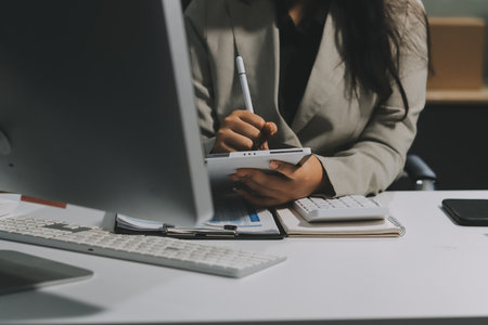 Asian Businesswoman Using laptop computer and working at office with calculator document on desk, doing planning analyzing the financial report, business plan investment, finance analysis concept.の写真素材