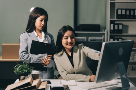 Asian Businesswoman Using laptop computer and working at office with calculator document on desk, doing planning analyzing the financial report, business plan investment, finance analysis concept.の写真素材