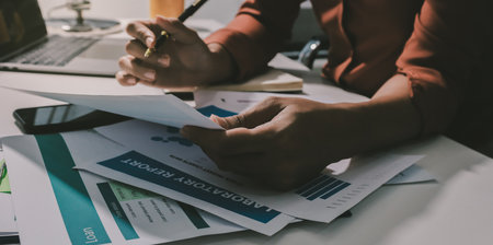 Working from home, Closeup business woman using laptop computer and analyzing financial report.の写真素材
