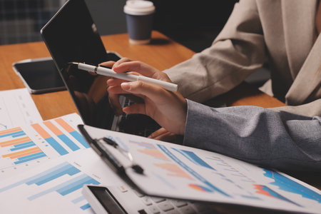 Group of confident business people point to graphs and charts to analyze market data, balance sheet, account, net profit to plan new sales strategies to increase production capacity.の写真素材