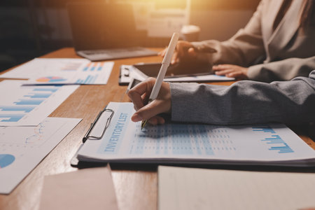 Group of confident business people point to graphs and charts to analyze market data, balance sheet, account, net profit to plan new sales strategies to increase production capacity.の写真素材
