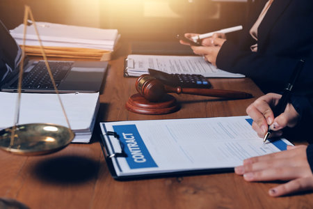 Attractive young lawyer in office Business woman and lawyers discussing contract papers with brass scale on wooden desk in office. Law, legal services, advice, Justice and real estate concept.の写真素材