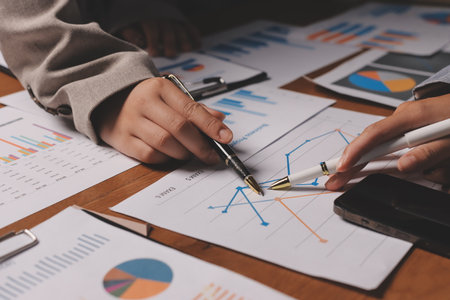 Group of confident business people point to graphs and charts to analyze market data, balance sheet,...