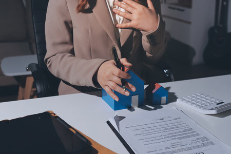 Female Real Estate Broker presenting and advised to 
model home and building project detail in the office, sign purchase sales contract, agreements concerned mortgage loan offer and insurance.の写真素材