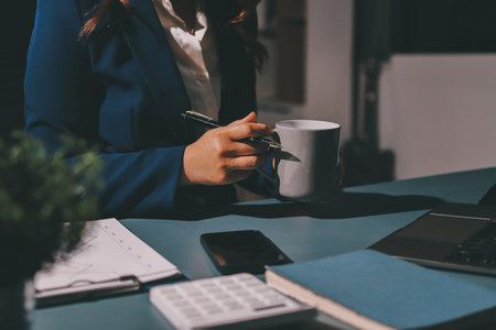 Expert woman asian female people review data number costing managerial account prepare monthly actual cost variance report at tax audit office. ESG sheet budget control ERP process service project.の写真素材