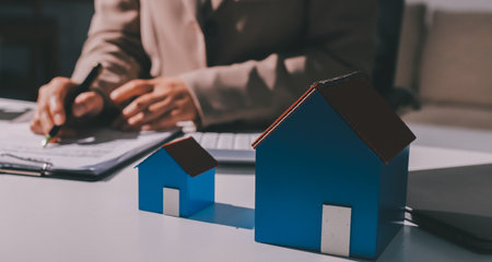 Female Real Estate Broker presenting and advised to model home and building project detail in the office, sign purchase sales contract, agreements concerned mortgage loan offer and insurance.の写真素材