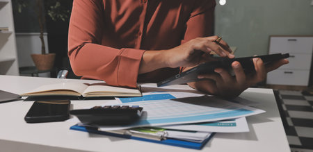 Working from home, Closeup business woman using laptop computer and analyzing financial report.の写真素材