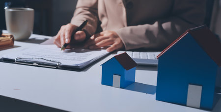 Female Real Estate Broker presenting and advised to 
model home and building project detail in the office, sign purchase sales contract, agreements concerned mortgage loan offer and insurance.の写真素材