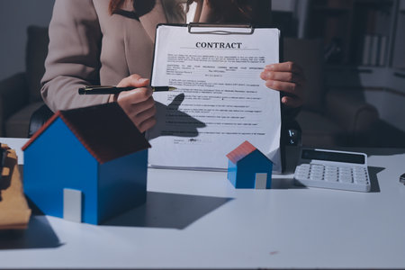Female Real Estate Broker presenting and advised to 
model home and building project detail in the office, sign purchase sales contract, agreements concerned mortgage loan offer and insurance.の写真素材