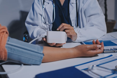 Nurse measuring blood pressure of elderly woman at table, closeup. Assisting senior generation