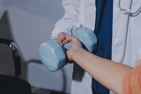 Physiotherapist training with patient using dumbbells in clinic,Physical therapy conceptの写真素材