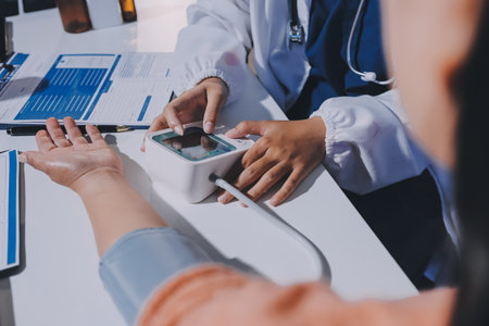 Nurse measuring blood pressure of elderly woman at table, closeup. Assisting senior generation