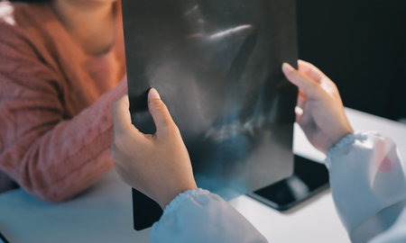 The doctor explains to the elderly patient about her lungs x-ray film and discusses the treatment method in a hospital setting using health and life insurance planning.の写真素材