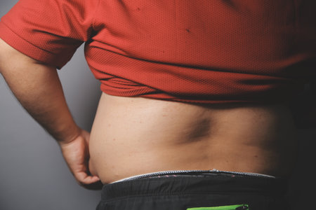 Fat man in front of a mirror looks at his body. Excess belly fat, Unhealthy lifestyle, Diet concept.