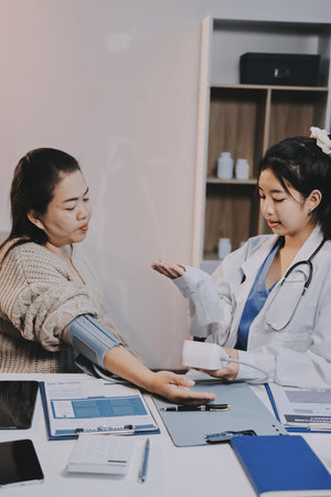 Doctor using sphygmomanometer with stethoscope checking blood pressure to a patient in the hospital.
