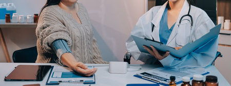 Doctor using sphygmomanometer with stethoscope checking blood pressure to a patient in the hospital.