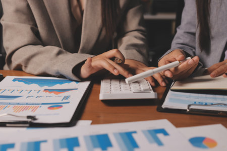 Group of confident business people point to graphs and charts to analyze market data, balance sheet, account, net profit to plan new sales strategies to increase production capacity.の写真素材