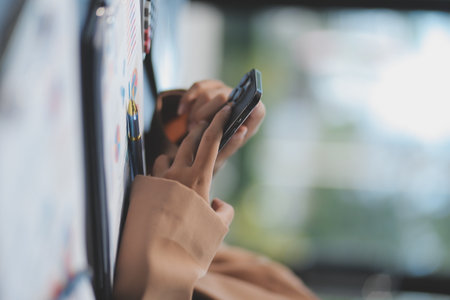 Young beautiful Asian businesswoman holding smartphone while working in the office room.の写真素材