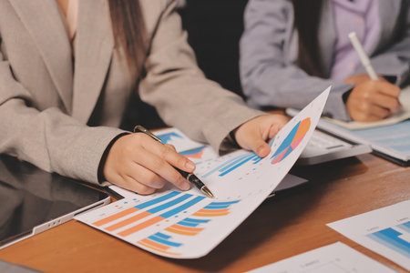 Group of confident business people point to graphs and charts to analyze market data, balance sheet, account, net profit to plan new sales strategies to increase production capacity.の写真素材