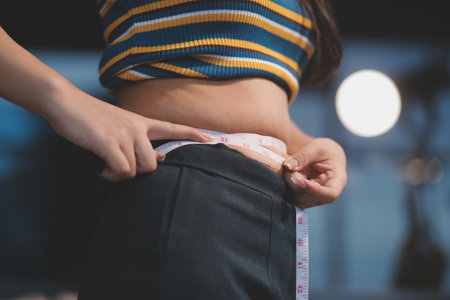 Cropped shot of woman touching and squeezing her belly.