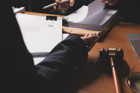 Attractive young lawyer in office Business woman and lawyers discussing contract papers with brass scale on wooden desk in office. Law, legal services, advice, Justice and real estate concept.の写真素材