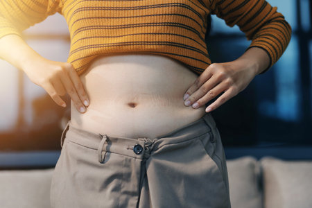 Cropped shot of woman touching and squeezing her belly.の写真素材