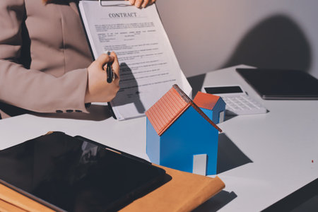 Female Real Estate Broker presenting and advised to 
model home and building project detail in the office, sign purchase sales contract, agreements concerned mortgage loan offer and insurance.の写真素材
