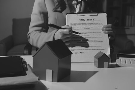 Female Real Estate Broker presenting and advised to model home and building project detail in the office, sign purchase sales contract, agreements concerned mortgage loan offer and insurance.の写真素材